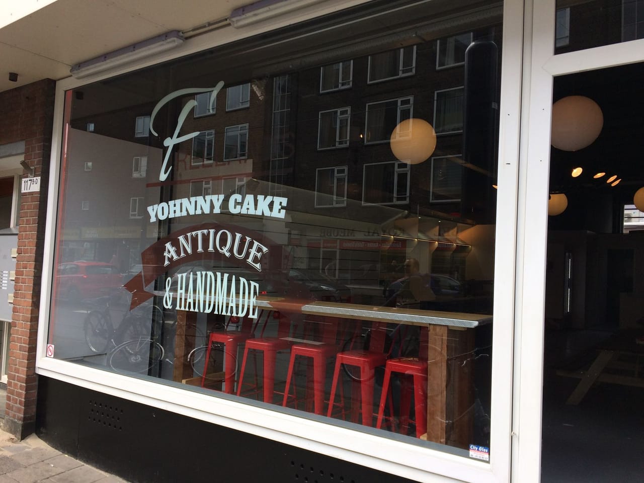 Raambelettering etalage Yohnny Cake cafe Rotterdam, handlettering en logo op groot etalageraam